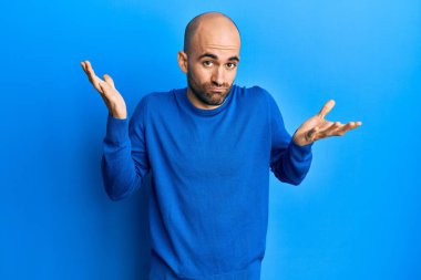 Günlük kışlık süveter giyen genç İspanyol adam habersiz ve kolları açık, hiçbir fikrim yok ve şüpheli bir yüzüm var. 