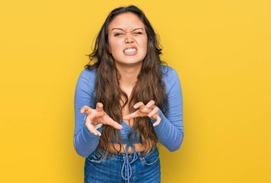 Gündelik kıyafetler giyen, komik gülümseyen genç İspanyol kız kedi gibi pençe hareketi yapıyor, agresif ve seksi bir ifade. 