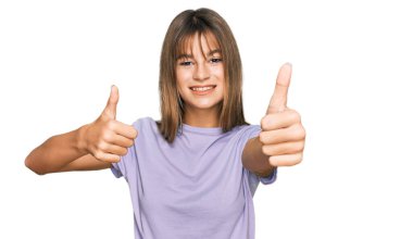 Kafkasyalı bir genç kız, günlük giysiler giyiyor. Elleriyle olumlu jest yapıyor. Gülümsüyor ve başarı için seviniyor. kazanan jest. 