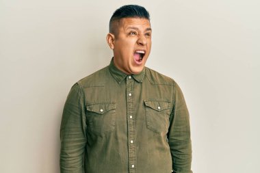 Gündelik kıyafetler giyen genç latin adam kızgın ve kızgın bağırıyor sinirli ve öfkeli, öfkeyle bağırıyor. öfke ve agresif konsept. 