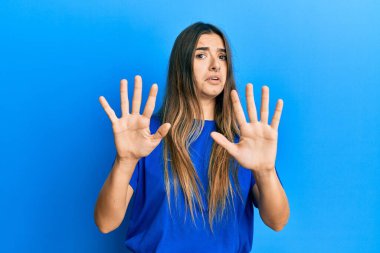 Günlük kıyafetler giyen genç İspanyol kadın korku ifadesinden korkuyor ve dehşete düşüyor. El hareketlerini durdur, şok içinde bağır. panik konsepti. 