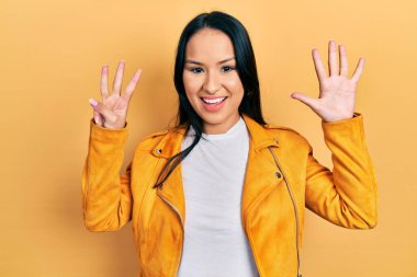 Burnu delinmiş, sarı deri ceketli güzel İspanyol bir kadın sekiz numaralı parmaklarıyla gülümseyerek mutlu ve kendinden emin bir şekilde onu işaret ediyor.. 