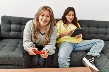 Gülümseyen genç çift video oyunu oynayıp evde touchpad kullanıyor..