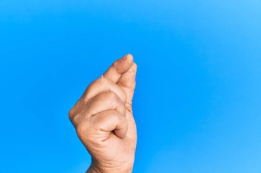 Mavi arka plan üzerinde yaşlı İspanyol adamın eli parmak, iş ve reklamla boş bir yer tutuyor. 