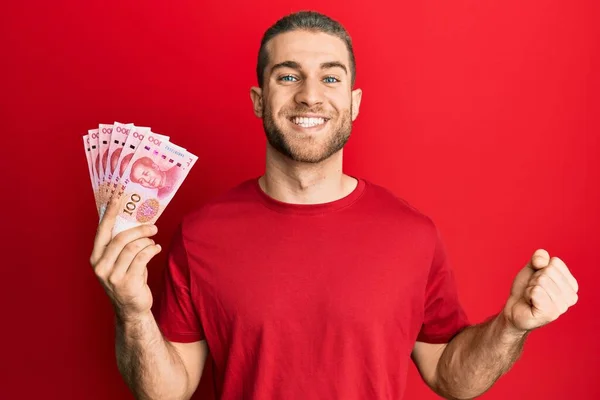 Joven Hombre Caucásico Sosteniendo Billetes Chinos Yuan Gritando Orgulloso Celebrando —  Fotos de Stock