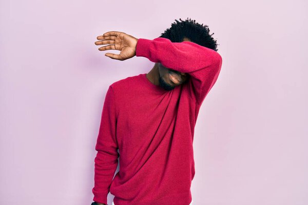 Young african american man wearing casual clothes covering eyes with arm, looking serious and sad. sightless, hiding and rejection concept