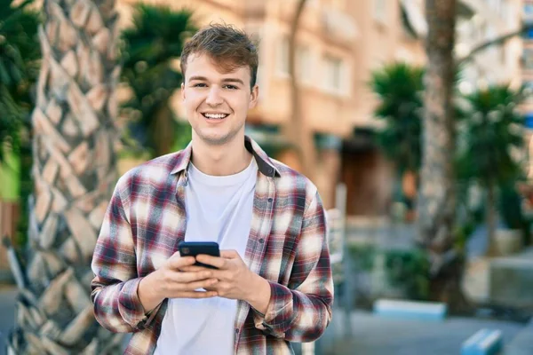 若い白人男性が市内のスマートフォンを使って笑顔で幸せ — ストック写真