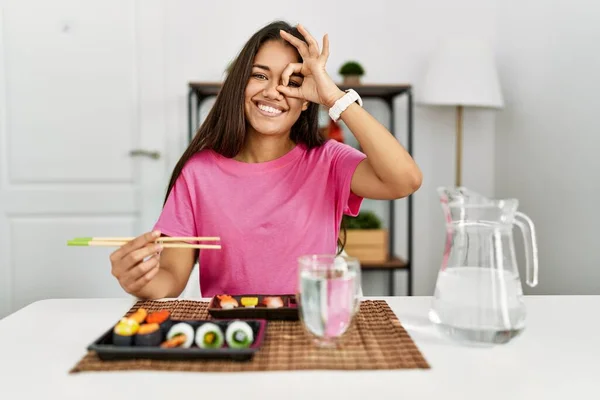 年轻的黑发女人用筷子吃寿司 做着手势 微笑着 用手指看着她 脸上洋溢着快乐的表情 — 图库照片