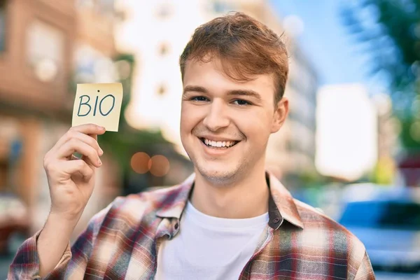 Joven Caucásico Sonriendo Feliz Sosteniendo Bio Recordatorio Papel Ciudad —  Fotos de Stock