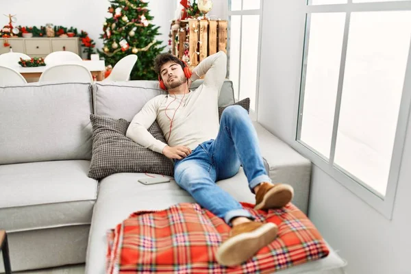 Jovem Hispânico Celebrando Natal Usando Fones Ouvido Deitados Sofá Casa — Fotografia de Stock