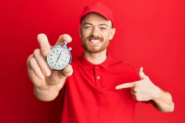 Ung Rödhårig Man Bär Leverans Uniform Och Nedräkning Klocka Peka — Stockfoto