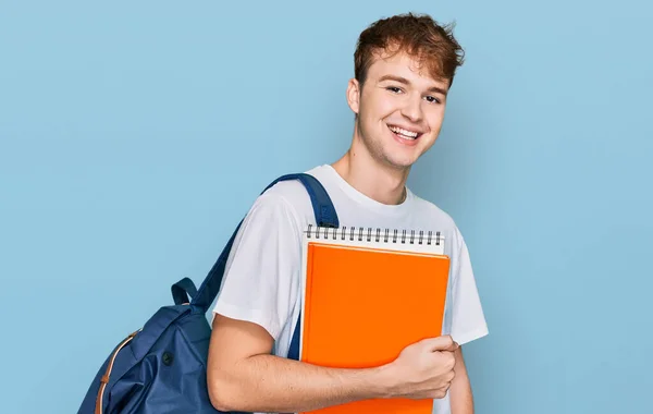 Młody Biały Mężczyzna Noszący Plecak Studencki Trzymający Książki Wyglądające Pozytywnie — Zdjęcie stockowe