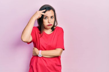 Orta yaşlı İspanyol kadın gündelik kıyafetler giyiyor. Alnındaki bir sorun yüzünden endişeli ve stresli. Kriz için endişeli. 