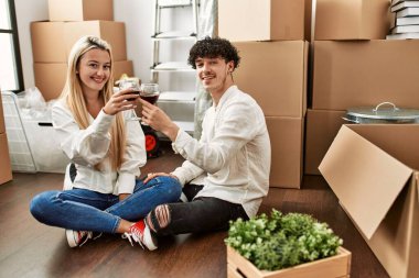 Genç ve güzel bir çift gülümsüyor. Yeni evlerinde kırmızı şarapla kadeh kaldırıyorlar.