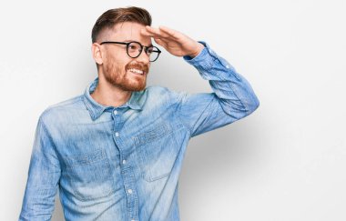 Genç, kızıl saçlı, rahat bir kot gömlek giyen mutlu ve gülümseyerek başını kaldırmış uzaklara bakıyor. arama kavramı. 