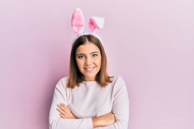 Paskalya tavşanı kulakları takan, kollarını kavuşturup kameraya gülümseyen güzel bir kadın. pozitif kişi. 