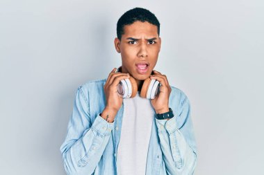Genç Afro-Amerikalı adam müzik dinlerken kulaklıklarını takmış, kuşkucu ve alaycı görünüyor, ağzı açık kalmış. 