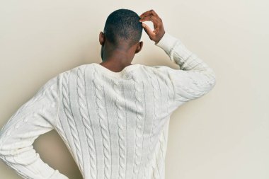 Genç Afrikalı Amerikalı bir adam günlük kıyafetlerini ters giyip elleri kafasında şüpheyi düşünüyor. 