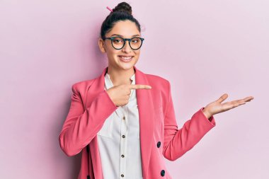 İş ceketi ve gözlük takan güzel ortadoğulu kadın kameraya hayret ediyor ve gülümsüyor.. 