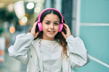 Şehirde kulaklık takıp gülümseyen İspanyol çocuk..