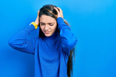 Balıkçı yaka kazak giyen genç esmer kız acı ve migren yüzünden çaresiz ve stresli bir baş ağrısı çekiyor. Eller başının üstünde.. 