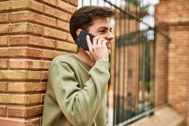 Genç İspanyol adam gülümsüyor. Şehirdeki akıllı telefondan konuşuyor..