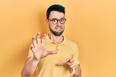 Gündelik kıyafetler ve gözlük takan genç İspanyol adam tiksindirici tepki verdiği için tiksinmiş ve korkmuş bir ifade takınıyordu. Eller havada. 