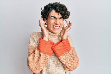 Gündelik kazak giyen İspanyol genç adam yüksek sesli müzik sesi için kulaklarını parmaklarıyla kapatıyor. sağır kavramı. 