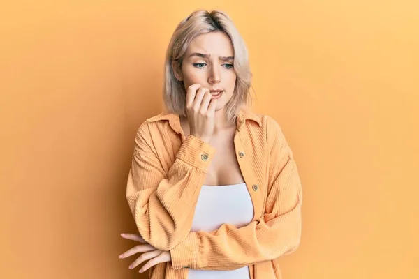 Młoda Blondynka Luźnych Ubraniach Wygląda Zestresowaną Zdenerwowaną Rękami Obgryzającymi Paznokcie — Zdjęcie stockowe