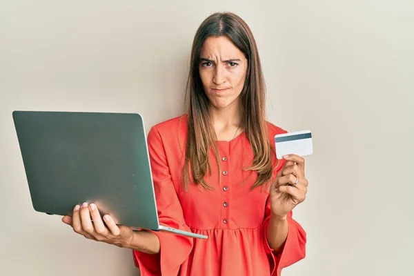 Młoda Piękna Kobieta Trzymająca Laptopa Kartę Kredytową Sceptyczna Nerwowa Marszcząca — Zdjęcie stockowe
