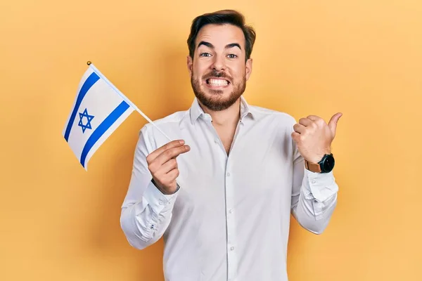 髭を生やしたハンサムな白人男性がイスラエルの旗を持っている親指を横に向けて笑顔幸せなオープン口で — ストック写真