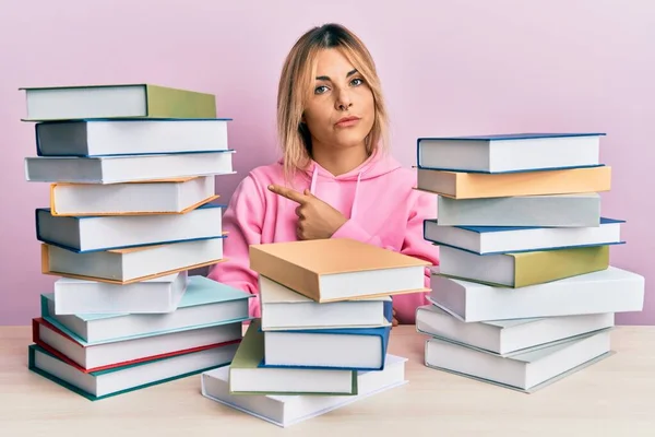 Young Caucasian Woman Sitting Table Books Pointing Hand Finger Side — Stock Photo, Image