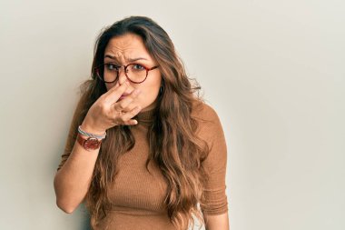 Günlük kıyafetler giyen ve gözlük takan genç İspanyol kız pis ve iğrenç bir koku alıyor. Nefesini burnunda tutuyor. Kötü kokuyor. 