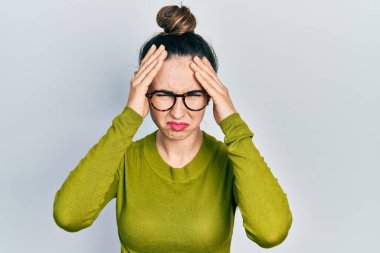 Günlük kıyafetler ve gözlük takan genç İspanyol kız baş ağrısı ve stres yüzünden acı çekiyor çünkü acı ve migren. Eller başının üstünde.. 