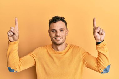 Yüzünde ciddi bir ifadeyle parmaklarını gösterip rahatlayan genç bir İspanyol. Basit ve doğal bir şekilde kameraya bakıyorsun.. 