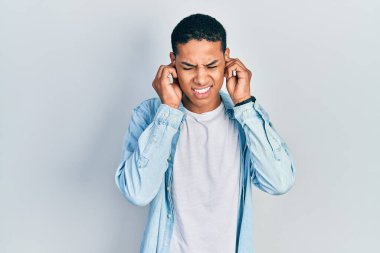 Genç Afro-Amerikan adam gündelik kıyafetler giyip yüksek sesli müzik sesi için kulaklarını parmaklarıyla kapatıyor. sağır kavramı. 
