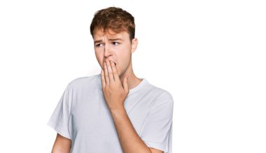 Gündelik beyaz tişört giyen genç beyaz adam ağzıyla esnemekten sıkılmış. Huzursuz ve uykulu.. 