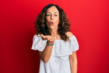 Orta yaşlı İspanyol kadın, gündelik kıyafetler giyip kameraya bakıyor ve havada el ele öpüşüyor. Güzel ve seksi. aşk ifadesi. 