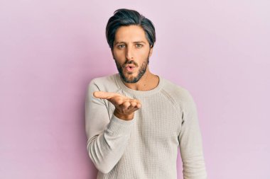 Sıradan bir kazak giyen genç İspanyol adam kameraya bakıp havada el sallayarak öpüşüyor ve çok güzel ve seksi. aşk ifadesi. 