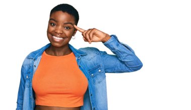 Genç Afro-Amerikan kadın, günlük giysiler içinde gülümseyerek tek parmakla, harika bir fikir ya da düşünceyle, iyi bir hafızayla işaret ediyor. 