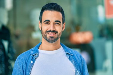 Genç İspanyol adam gülümseyerek şehirde mutlu mesut dikiliyor..