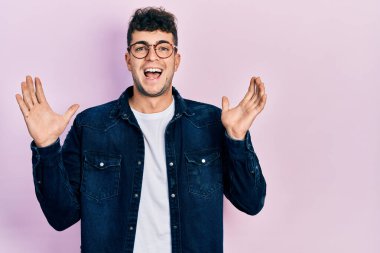 Gündelik kıyafetler giyen ve gözlük takan genç İspanyol adam çılgın kutlamalar yapıyor ve başarıya hayret ediyor. Kolları açık, gözleri açık heyecanla bağırıyor. Kazanan konsept 