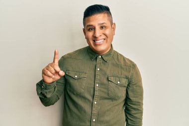 Gündelik kıyafetler giyen genç latin adam başarılı bir fikri işaret ediyor. Heyecanlı ve mutlu. Bir numara.. 