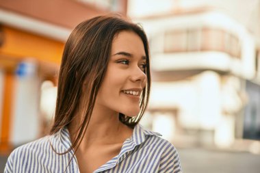 Genç İspanyol kız gülümseyerek şehirde mutlu mesut dikiliyor..