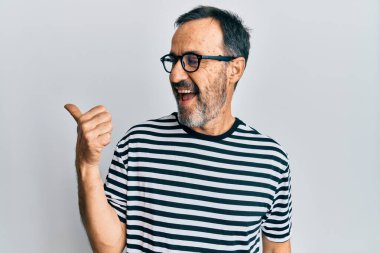 Orta yaşlı İspanyol bir adam, günlük kıyafetler ve gözlük takıyor. Parmağını kaldırıyor, gülümsüyor, ağzı açık. 