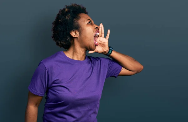 アフリカ系アメリカ人の女性は カジュアルな紫色のTシャツを着て大声で叫び 口の中で手で横に大声で叫んでいる コミュニケーションの概念 — ストック写真