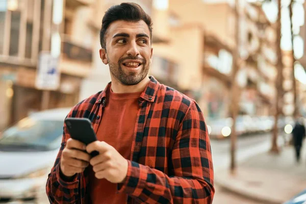 Joven Hombre Hispano Sonriendo Feliz Usando Smartphone Ciudad —  Fotos de Stock