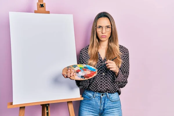 画家のイーゼルによってパレットで描画立って美しいヒスパニック系の女性は 問題のために動揺を眉をひそめて 懐疑的かつ緊張立っている 否定的な人 — ストック写真