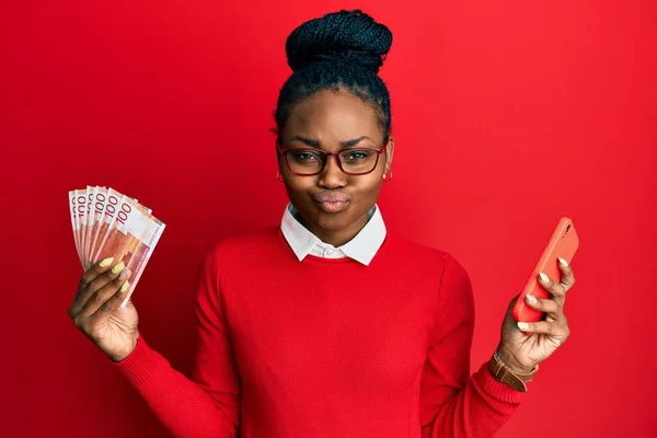 Young African American Woman Using Smartphone Holding Norwegian Krone Banknotes — Stock Photo, Image