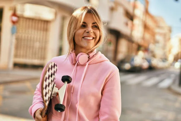 Jovem Menina Skatista Loira Sorrindo Feliz Segurando Patins Cidade — Fotografia de Stock